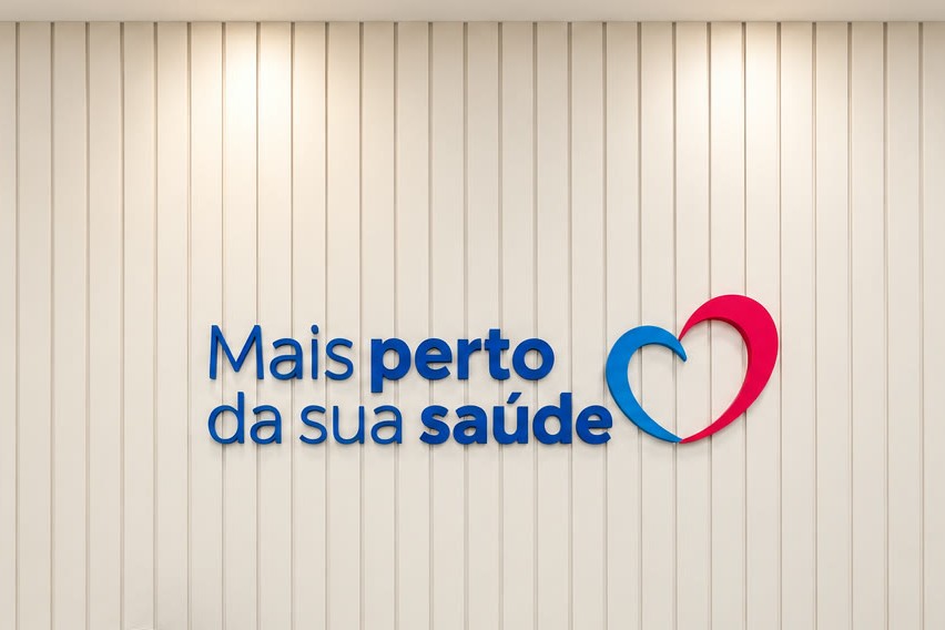 Recepção da Corbe, com a frase Mais perto da sua saúde e o coração na parede ripada, balcão com cantinho do café e cadeiras de espera